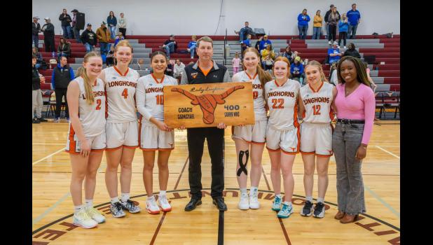 Coach Carmichael ... with current FHS Lady Longhorn seniors. Holding hand made plaque from bleachers out of the old gym and a girls basketball. Photo courtesy Heather Senn