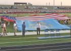 The dedication of the Wall School District’s outdoor athletic facility included volunteers holding up a huge American flag, as well as a slightly smaller South Dakota state flag.